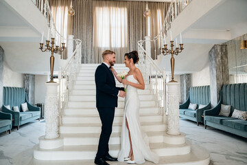 Beautiful and happy bride and groom on a large beautiful staircase.