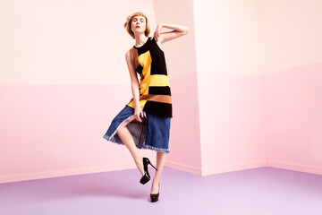 Fashionable woman in colorful outfit posing in a modern studio.