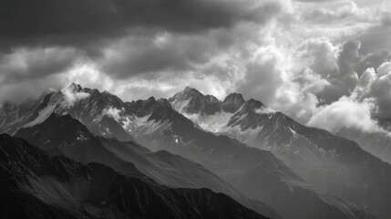 Obraz premium A monochrome view of a mountain range with snow capped peaks under a cloudy and dramatic sky view