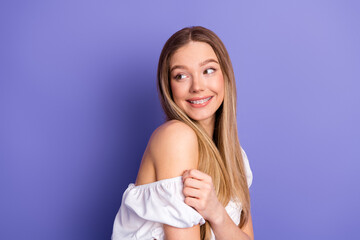 Smiling young woman in casual white outfit posing against a vibrant purple background radiating...