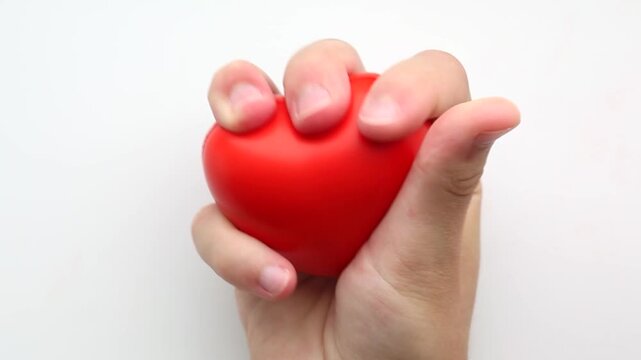Fingers close firmly around the heart squishy, deforming its shape. Each movement shows firm pressure and rebound, emphasizing stress release effect.