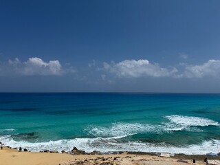 A beautiful tropical seascape of blue ocean and sky with clouds over a sandy beach