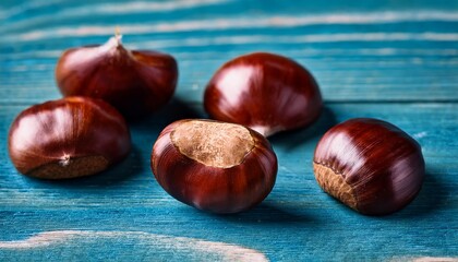 Obraz premium close up of chestnuts on a vibrant blue wood texture perfect for conveying a sense of autumn the rich colors of the chestnuts provide a beautiful contrast against the textured background