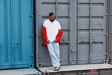 African american man in red windbreaker jacket standing near cargo containers 