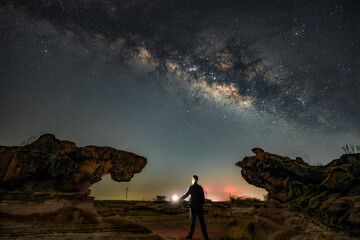 Silhouette with Lantern Under Milky Way in Desert Landscape