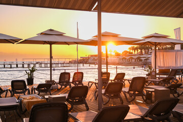Scenic sunset view over the Mediterranean sea from a private resort pier with umbrellas and lounge chairs for a tranquil vacation.