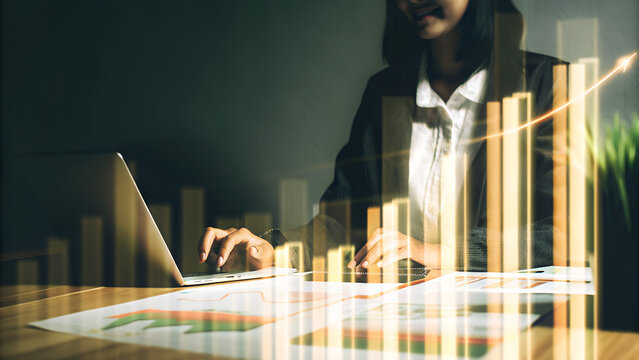 Businesswoman calculating financial reports and analyzing growth charts, symbolizing business and investment - Powered by Adobe