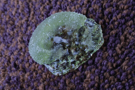 A green sticky residue is visibly smudged on a soft fabric surface alongside colorful gummy candies. The setting appears warm and inviting, perfect for a treat.