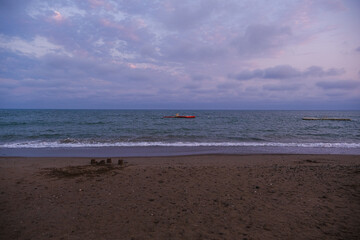 Calm sea with waves on a beach at dusk. Water with blue sky and light clouds. Nature, travel, and vacation concept.