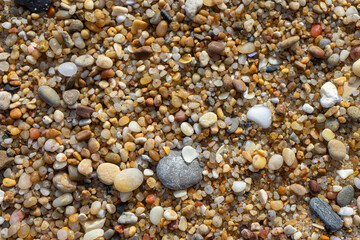 Close-up of sand grains and pebbles on the beach, natural texture background for design and nature concepts.