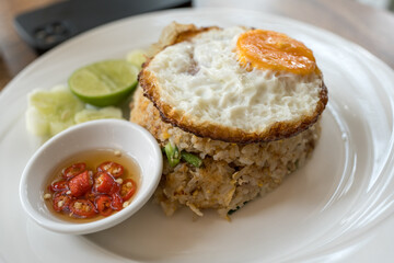 Thai dish of Khao pad moo fried rice served with chilli with fish sauce and topped with a crispy fried egg