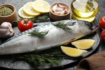 Fresh raw mackerel and spices on black table, closeup. Seafood delicacies