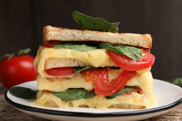 Delicious sandwiches with melted cheese, spinach and tomatoes on wooden table, closeup