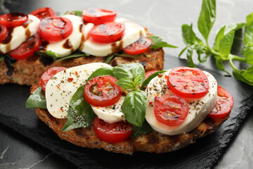 Delicious sandwiches with mozzarella cheese, tomatoes and basil on table, closeup