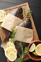 Fresh raw flounder fish and spices on black wooden table, top view. Seafood