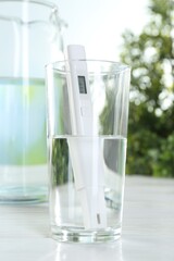 Nitrate tester in glass of water on white wooden table, closeup