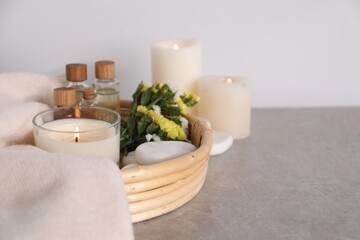 Spa composition with burning candles on light grey table, closeup. Space for text