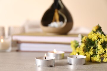 Spa composition with burning candles on wooden table against beige background, closeup