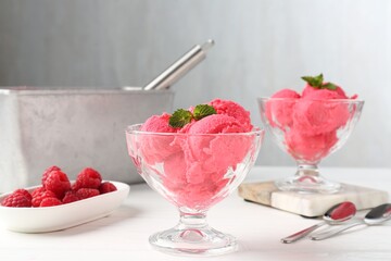 Delicious raspberry sorbet with mint in dessert bowls and fresh berries on white wooden table against light grey background, closeup