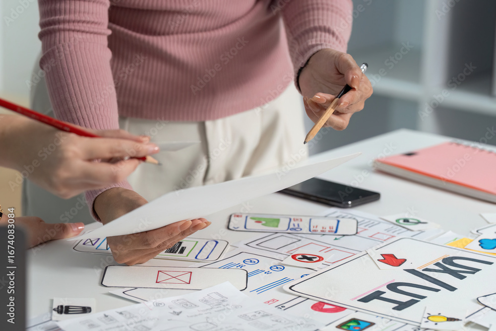 Aufkleber ux and ui design process. close-up of hands reviewing sketches in a collaborative workspace.