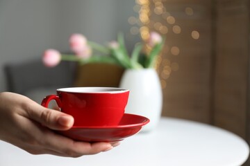 Woman with cup of tea at home, closeup