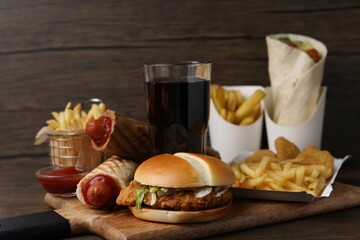 Naklejka na ściany i meble Different delicious fast food and cola on wooden table, closeup