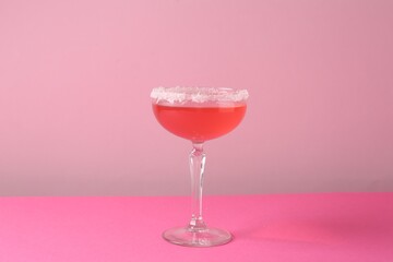 Martini cocktail with sugar in glass on pink background