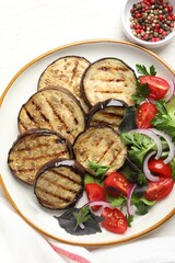 Grilled slices of eggplant with salad and peppercorns on white table, top view