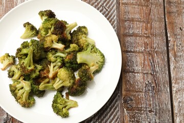 Tasty fried broccoli on wooden table, top view. Space for text