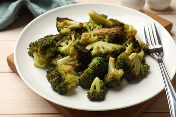 Tasty fried broccoli and fork on light wooden table, closeup