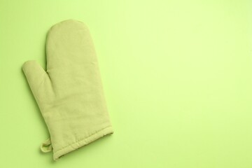 One oven glove on green background, top view. Space for text