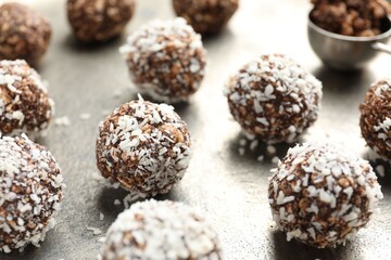 Tasty chocolate candies with nuts and coconut flakes on grey table, closeup