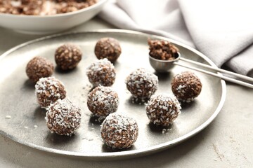 Tasty chocolate candies with nuts and coconut flakes on light table, closeup