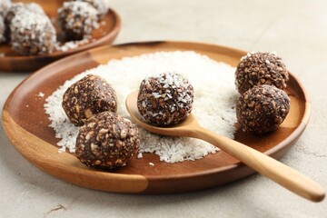 Making tasty chocolate candies with nuts and coconut flakes at light table, closeup