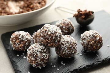 Tasty chocolate candies with nuts and coconut flakes on light table, closeup