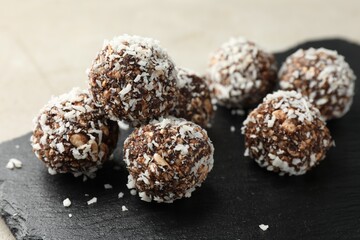 Tasty chocolate candies with nuts and coconut flakes on light table, closeup