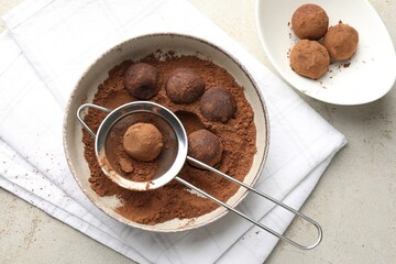 Making tasty chocolate candies with cocoa powder at light table, flat lay