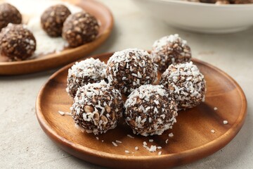 Tasty chocolate candies with nuts and coconut flakes on light table, closeup