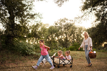 Family enjoying a leisurely walk in the park with their pet dog pulling a wagon