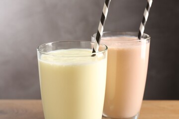 Tasty milkshakes in glasses on wooden table, closeup