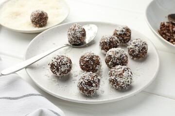 Tasty chocolate candies with nuts and coconut flakes on white wooden table, closeup