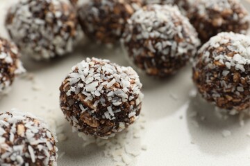 Tasty chocolate candies with nuts and coconut flakes on plate, closeup