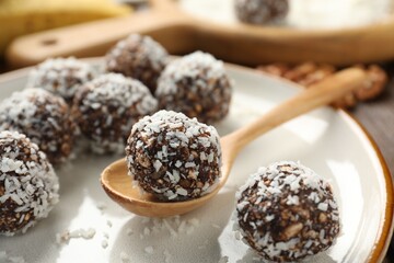 Tasty chocolate candies with nuts and coconut flakes on table, closeup