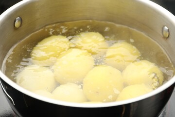 Young potatoes boiling in pot on stove, closeup