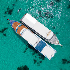 Aerial view of two recreational vessels or scuba diving boat anchoring together over turquoise...