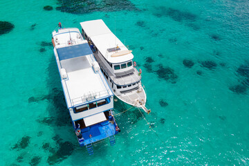 Aerial view of two recreational vessels or scuba diving boat anchoring together over turquoise...
