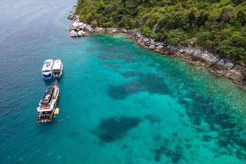 Group of recreational vessels or scuba diving boats anchoring over turquoise clear water at Racha...
