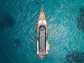 Aerial view of scuba diving boat or recreational vessel anchoring over turquoise clear water at...