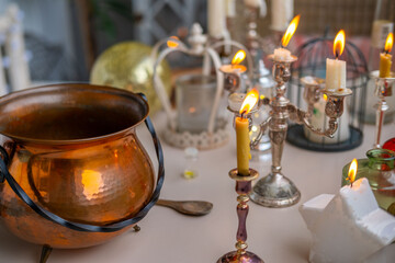 Halloween celebration Witchy Halloween setup with copper vintage pot cauldron, boiling potion, candles in holders, fantasy scene with candles, Spooky party, magical mood
