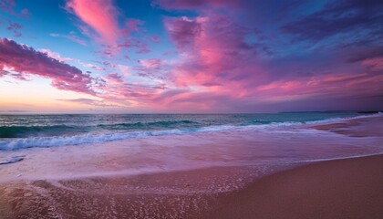 gentle waves wash over a pink hued beach under a breathtaking sky filled with colorful clouds at dusk
